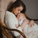 Mãe segurando seu bebê no colo em uma cadeira de balanço, representando o vínculo emocional e a importância do apoio durante o pós-parto