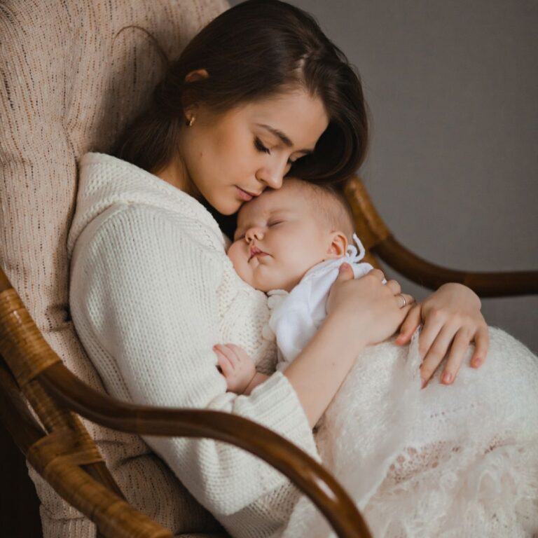 Mãe segurando seu bebê no colo em uma cadeira de balanço, representando o vínculo emocional e a importância do apoio durante o pós-parto